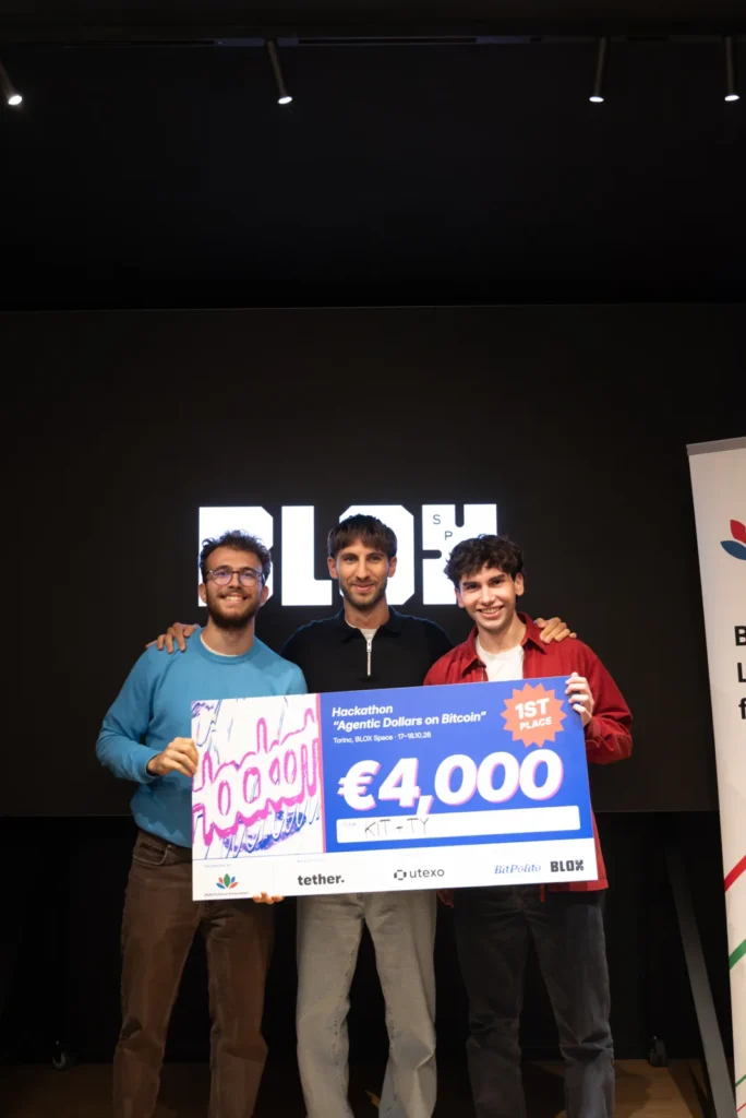 RGB hackathon 2026 first place: team Kit+ty on stage at BLOX, Turin, with the prize for the shared kitty app for group trips